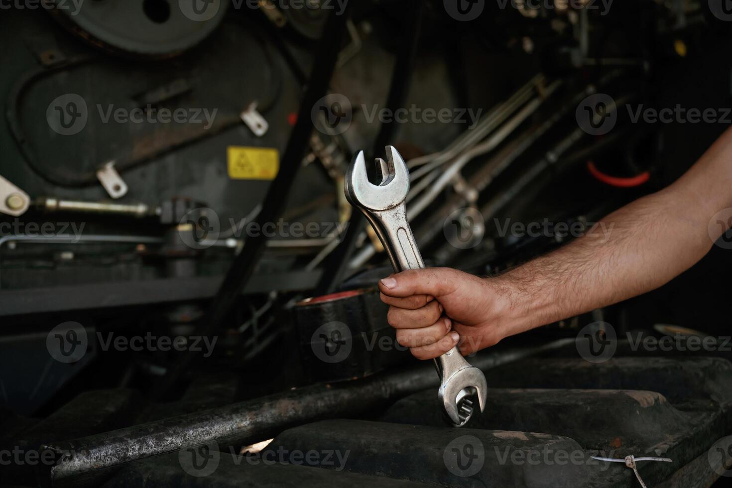Close up view,. Mechanic's hand fixing machinery with wrench in workshop photo