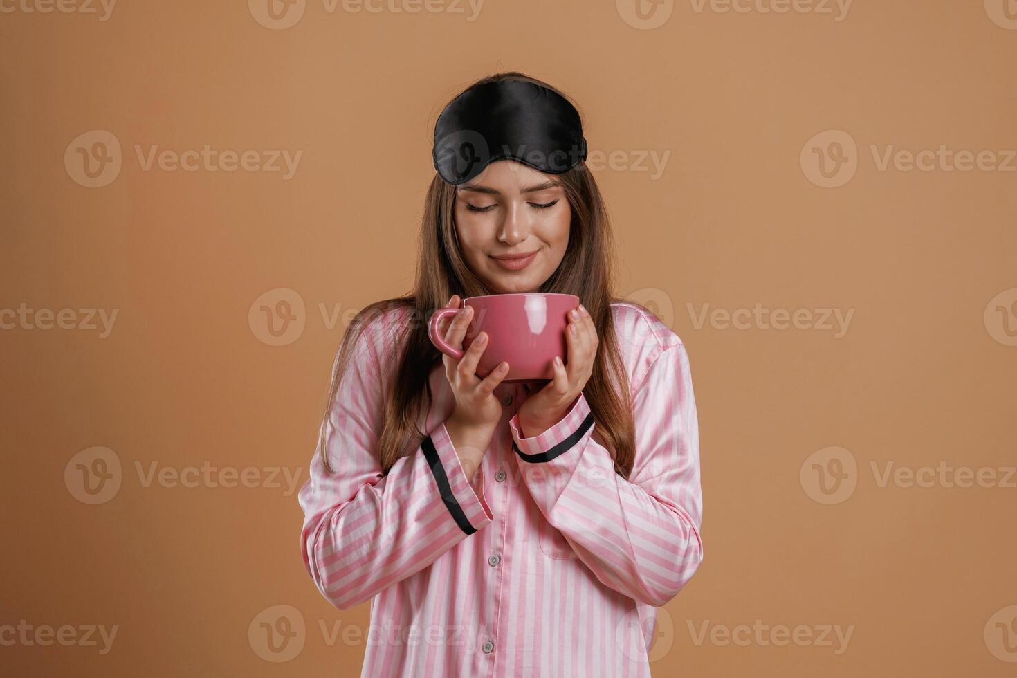 Pink ,pajama, with ,,cup of drink. Young pretty woman is against background in the studio photo