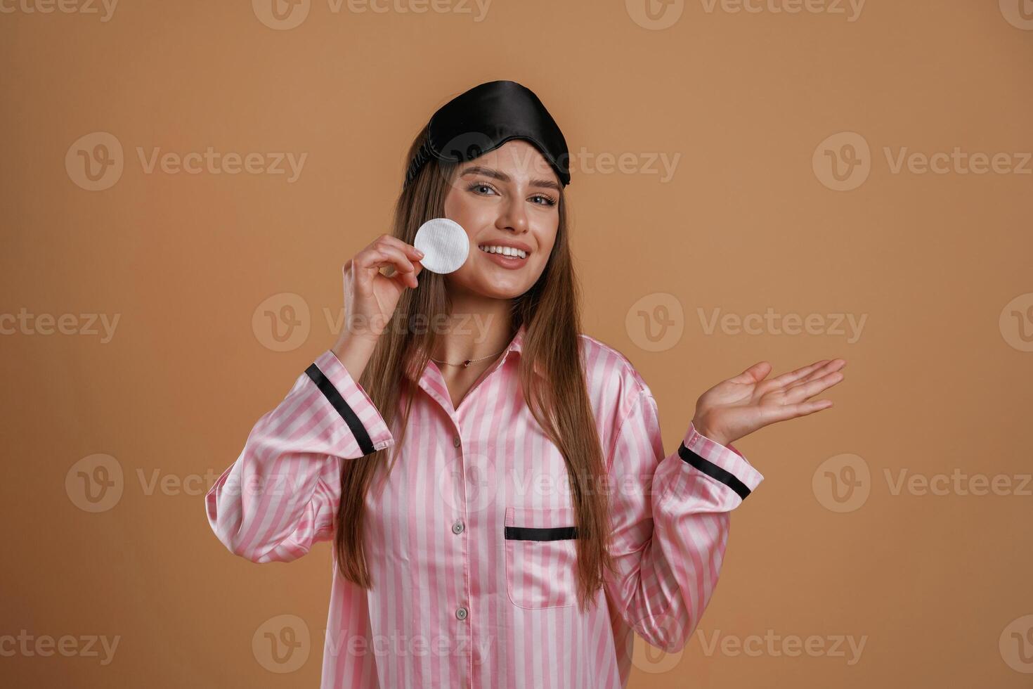Skin care morning routine,, in pink pajama. Young pretty woman is against background in the studio photo