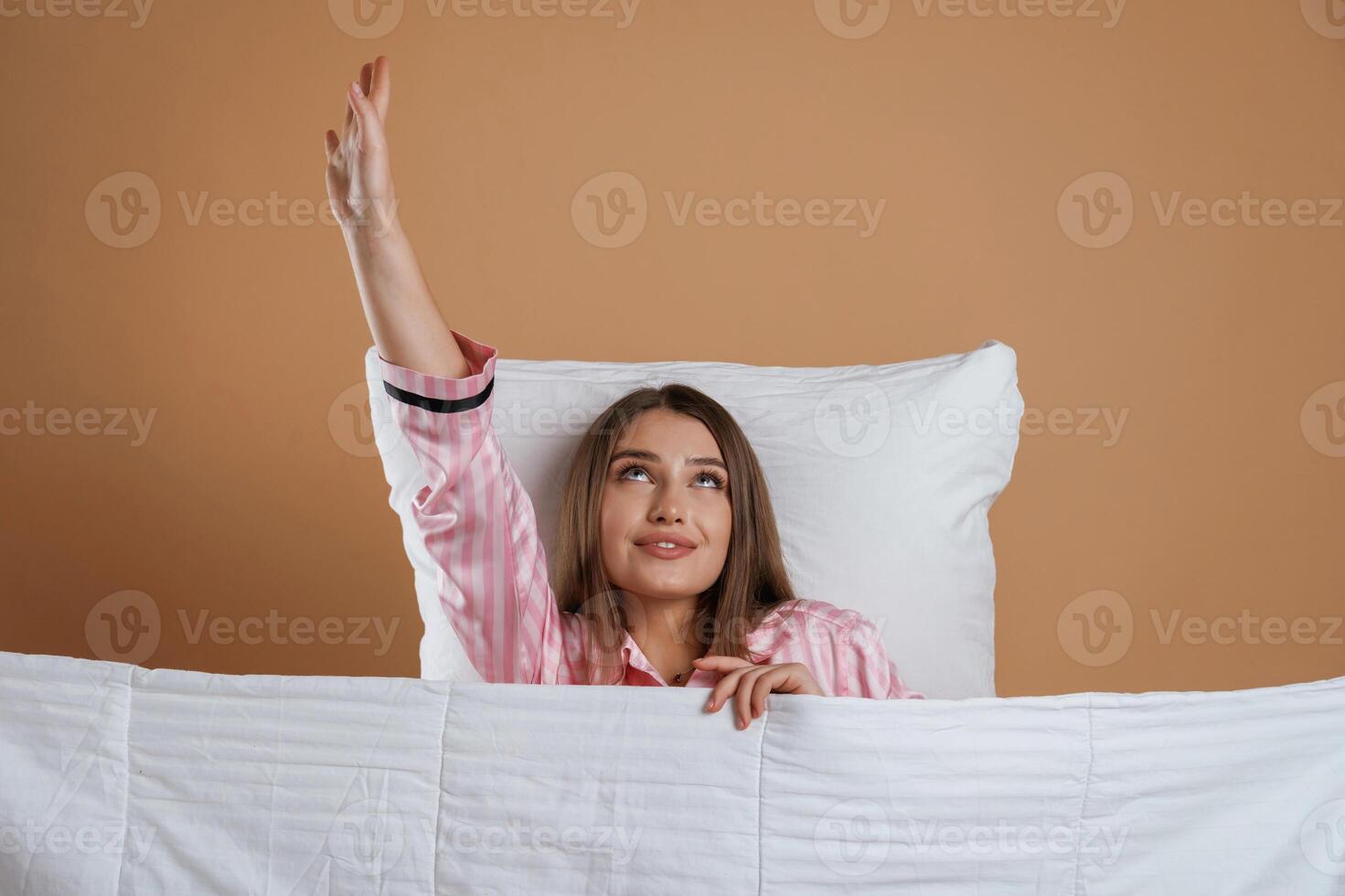 Lying ,,down on the pillow, in pajama. Young pretty woman is against background in the studio photo