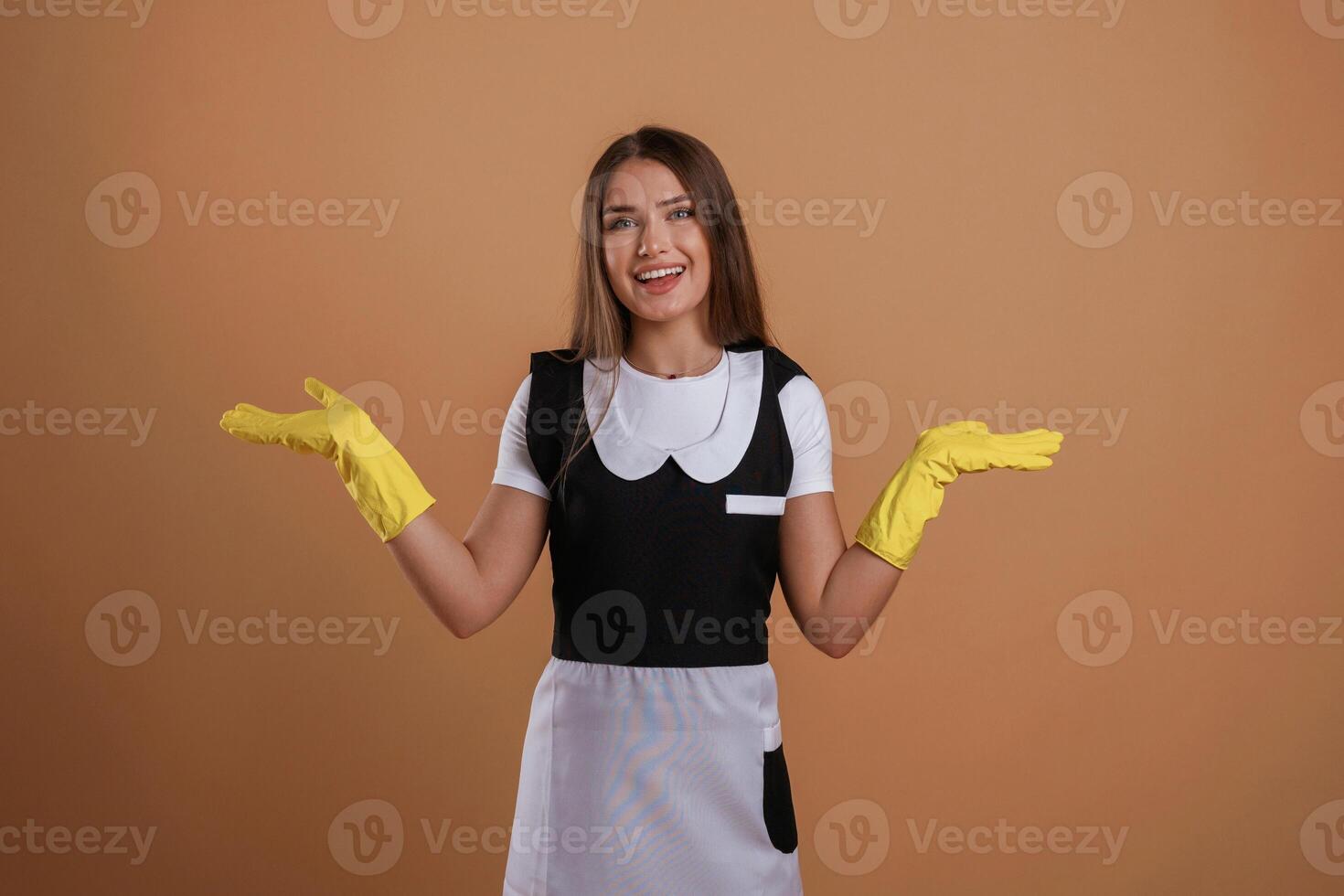Brown backdrop, chambermaid is standing... Young pretty woman is against background in the studio photo