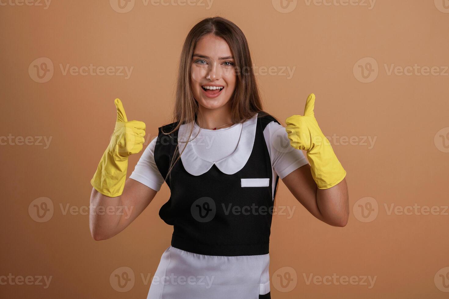 Brown backdrop,,, chambermaid is standing. Young pretty woman is against background in the studio photo