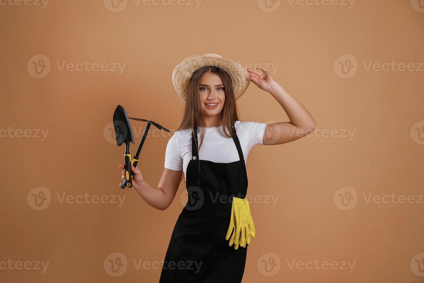 Labor conception. Gardener is, with ,tools. Young pretty woman is against background in the studio photo