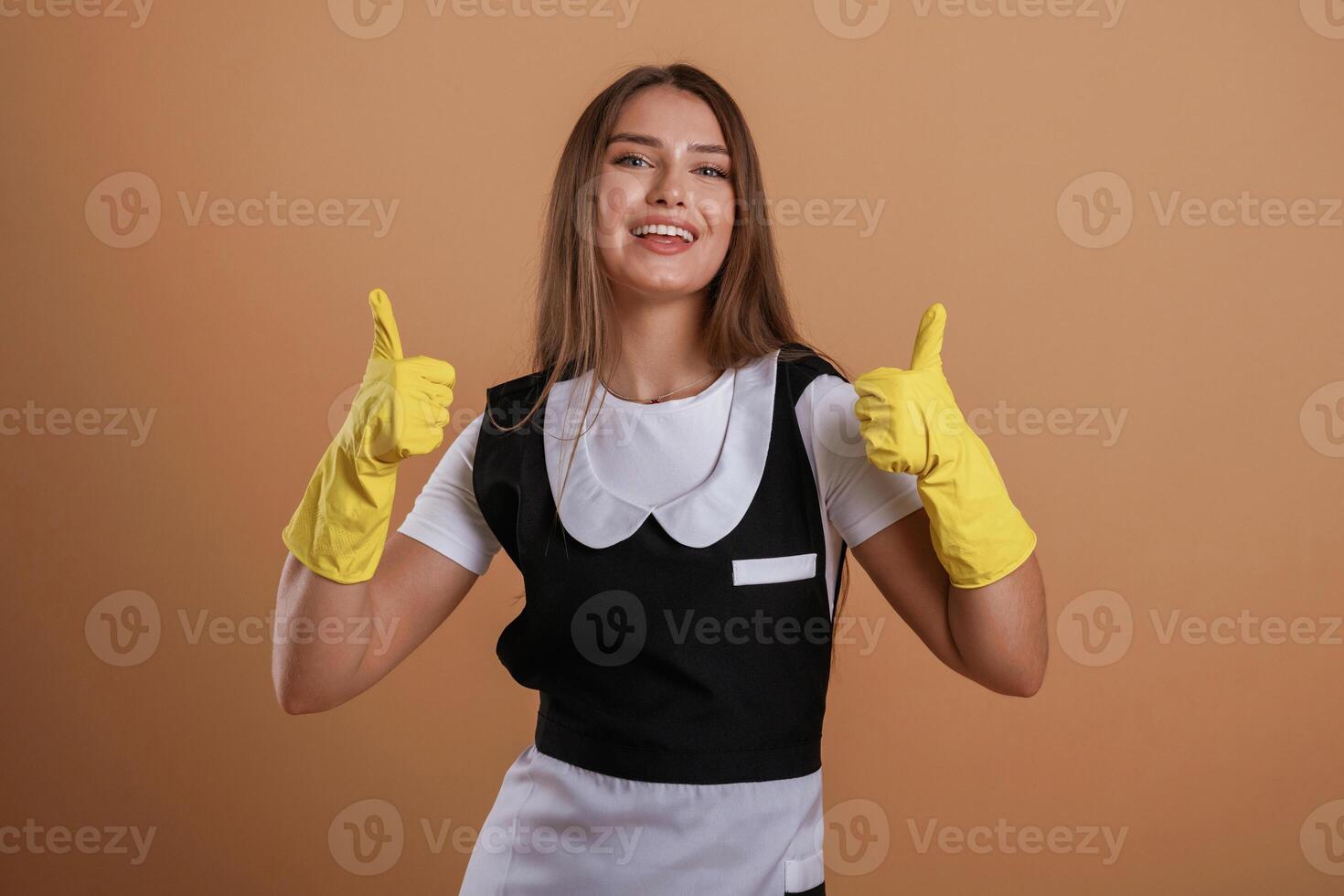 Brown, backdrop, chambermaid is standing. Young pretty woman is against background in the studio photo