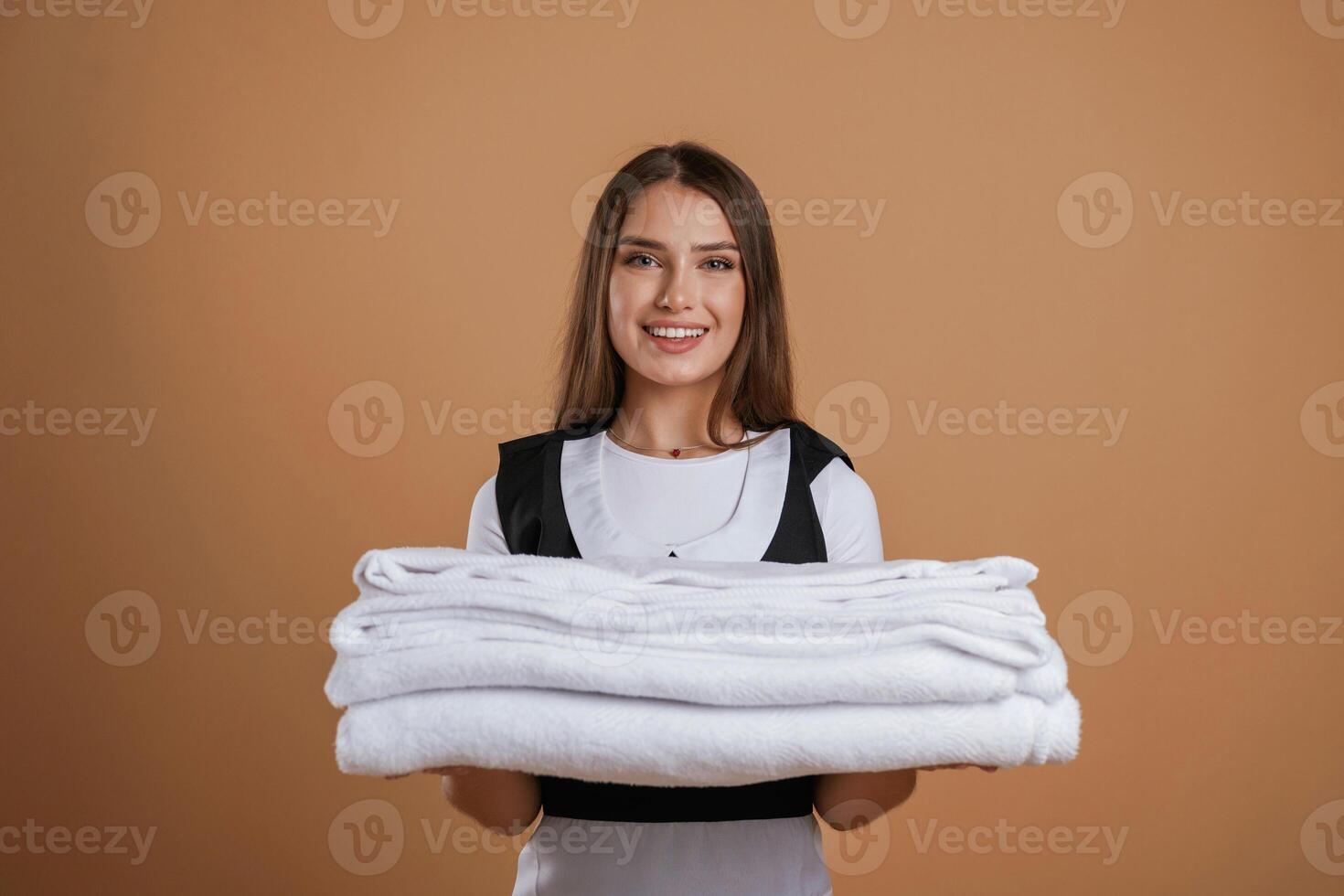 Brand ,,new, towels, chambermaid is standing. Young pretty woman is against background in the studio photo