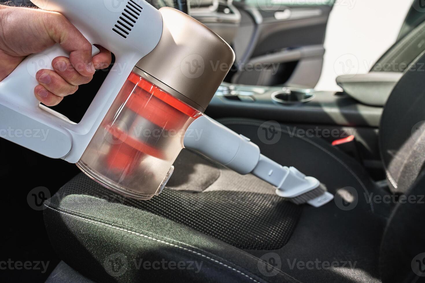 Cleaning car seat with handheld vacuum cleaner photo