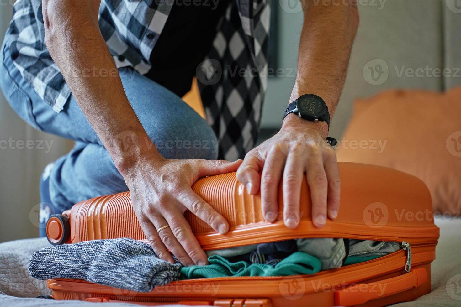 Man trying to close over packed suitcase before trip photo