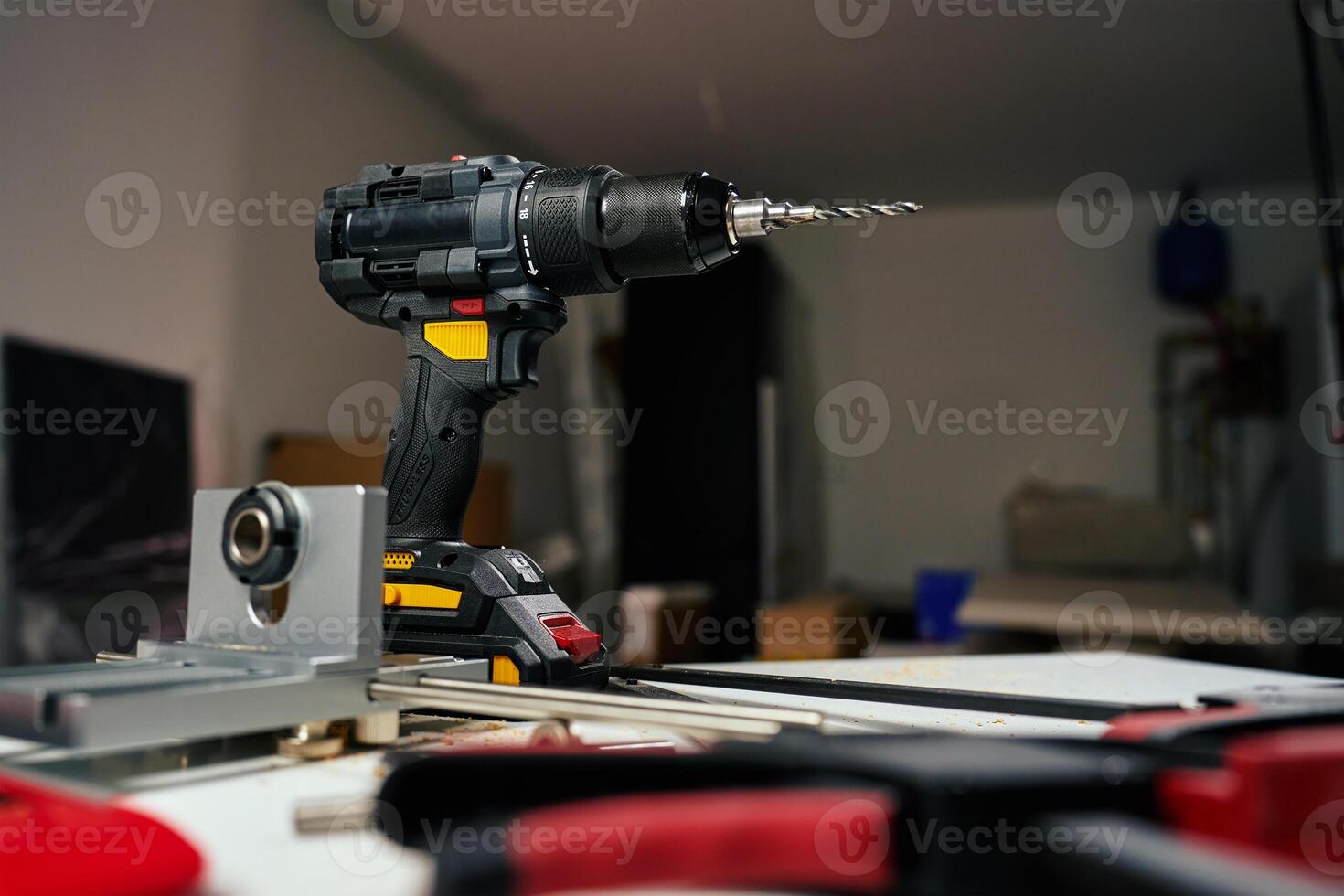 Electric cordless drill with bits and hand tools on workbench in workshop. Home renovation, construction and repair concept photo