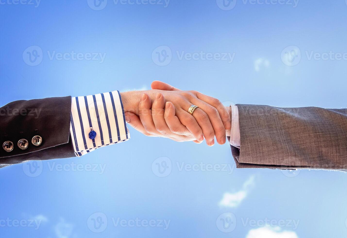 Closeup of a business handshake over sky background photo