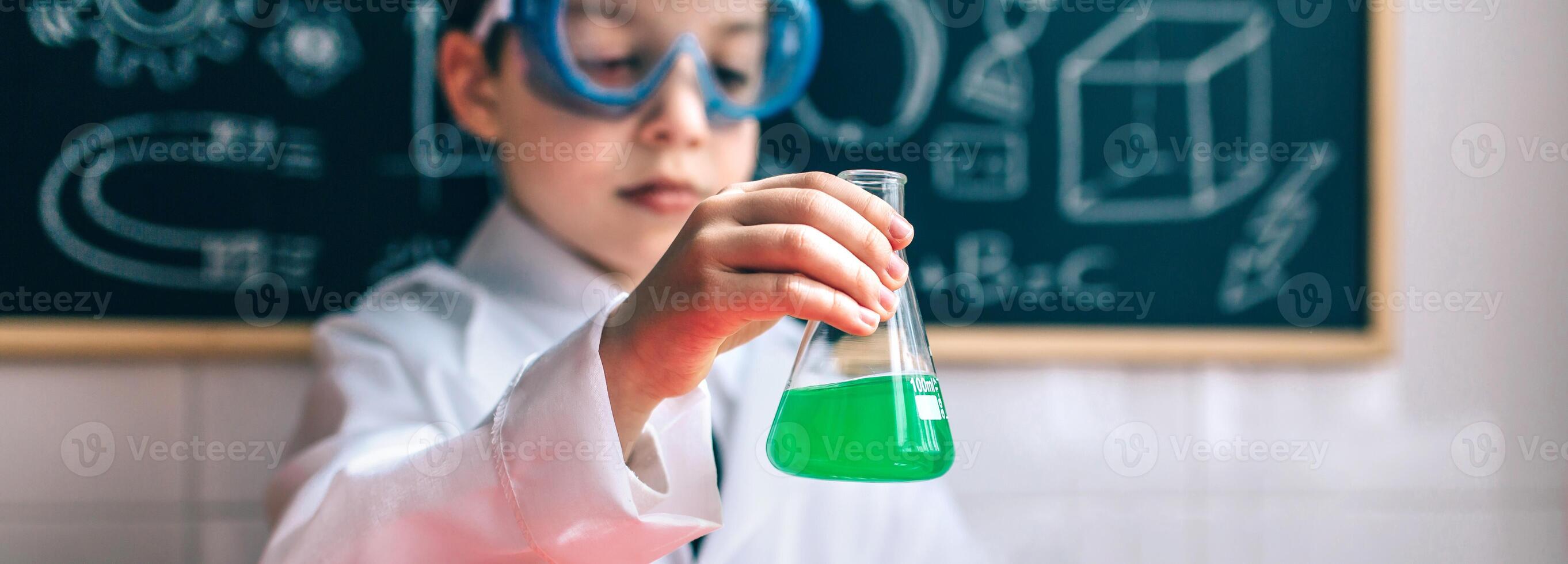 Serious boy holding flask with the chemical liquid photo