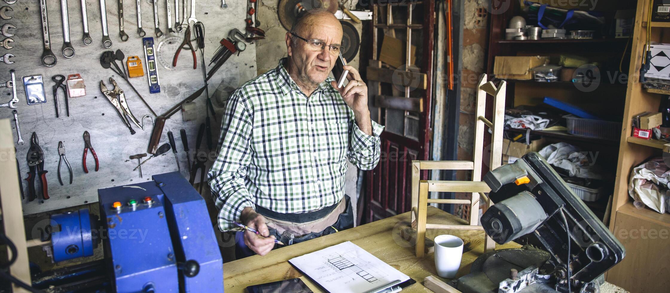 Carpenter talking with phone in his workshop photo