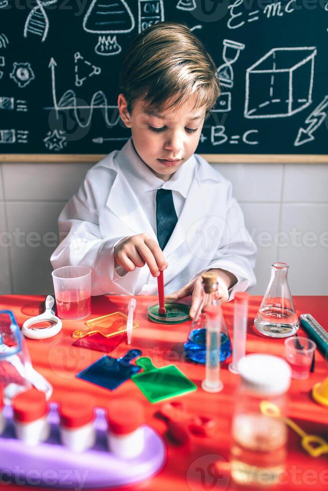 Kid playing as chemist with colorful liquids photo