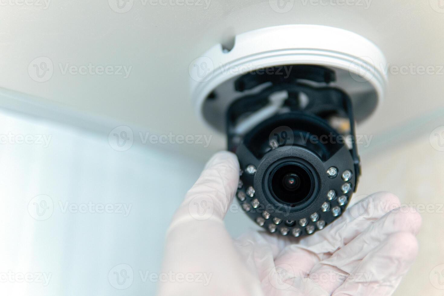 Close-up of the installation of a surveillance camera, a male hand in a white glove holds a surveillance camera photo