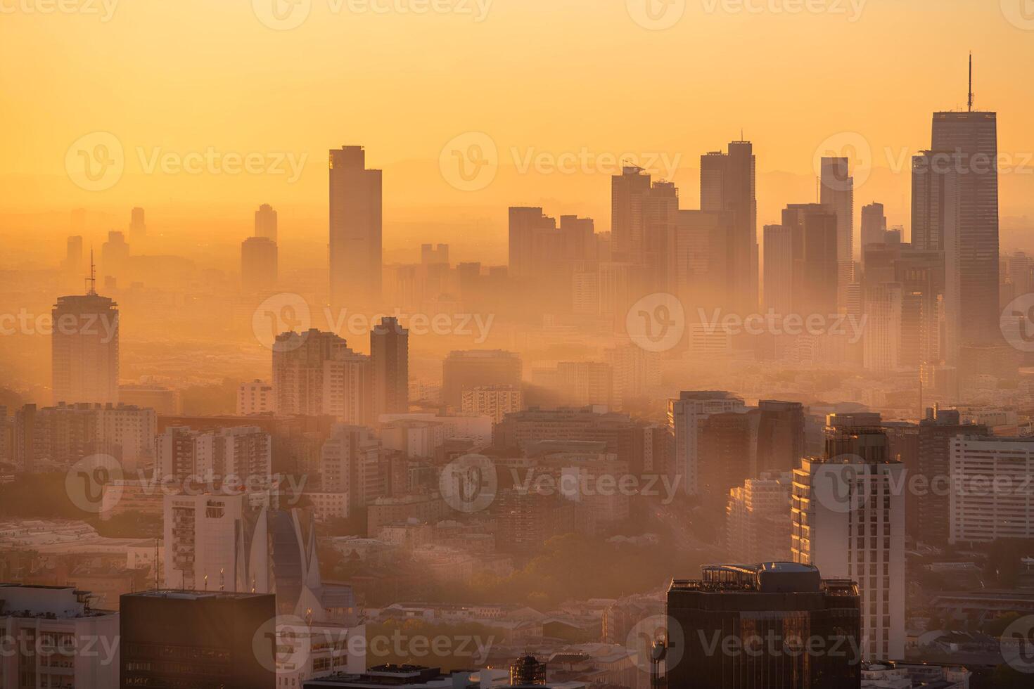 City skyline silhouette against hazy orange sunset sky photo