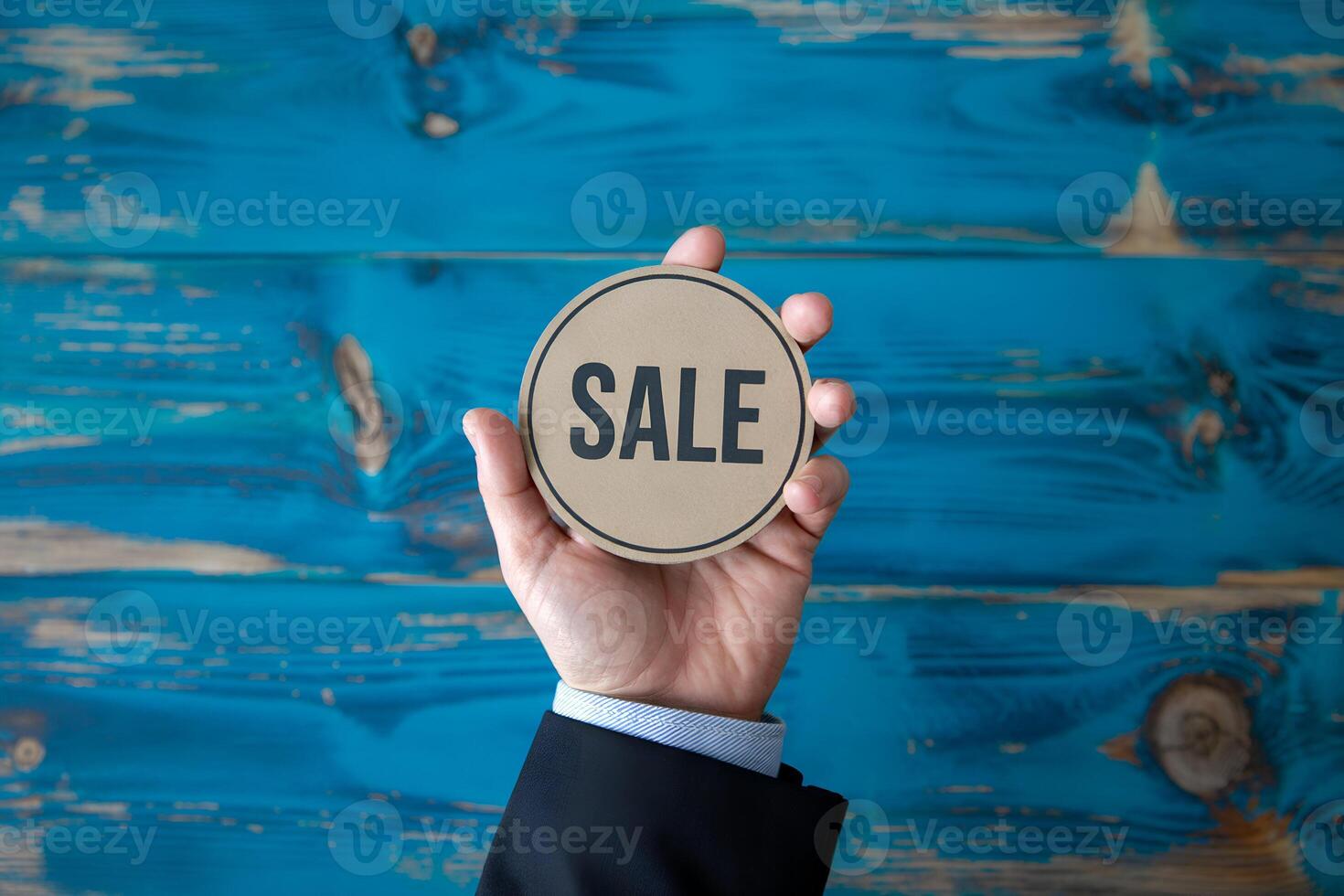 Hand holding tan SALE sign on turquoise wood photo