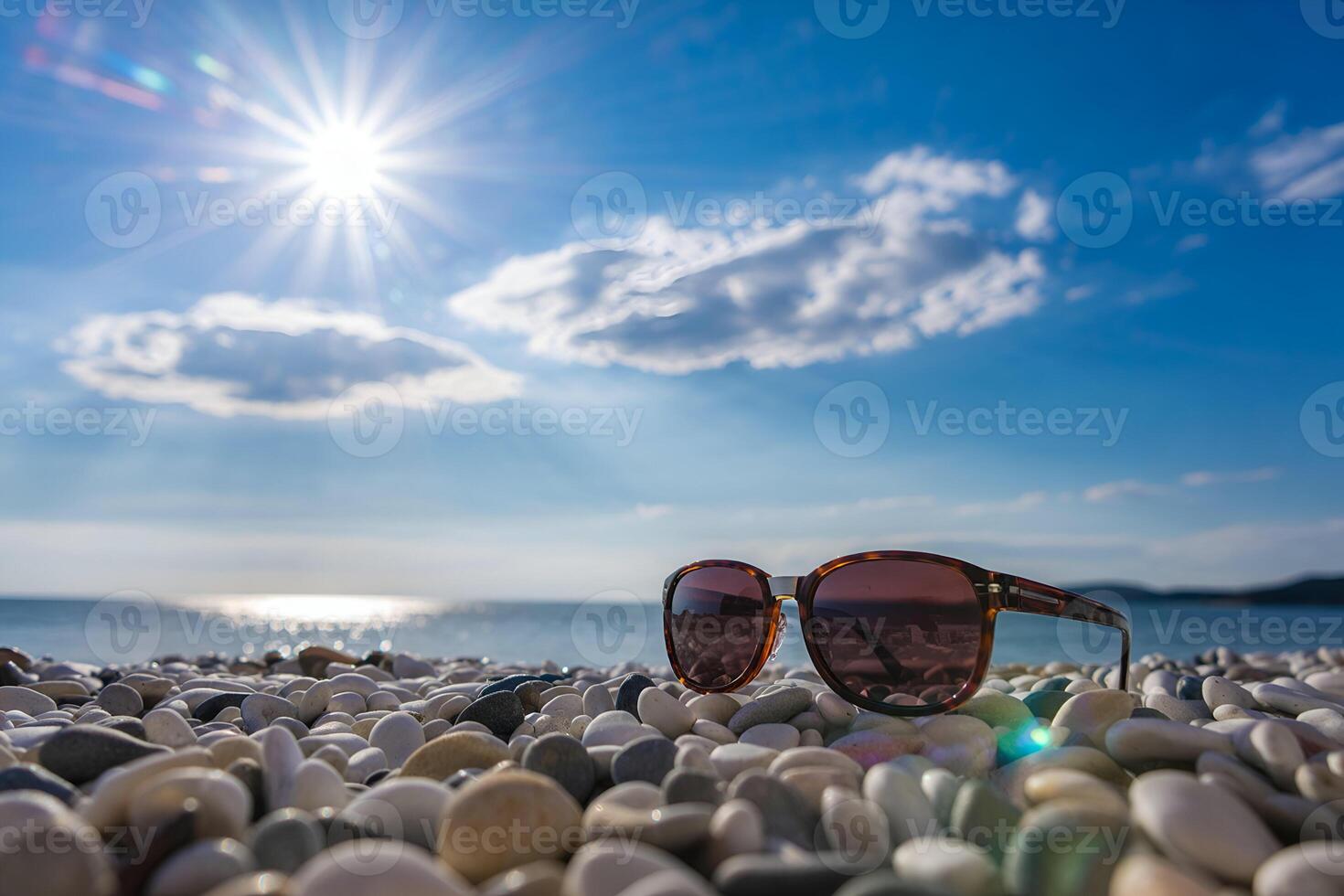Sunglasses on beach pebbles with ocean sunset photo