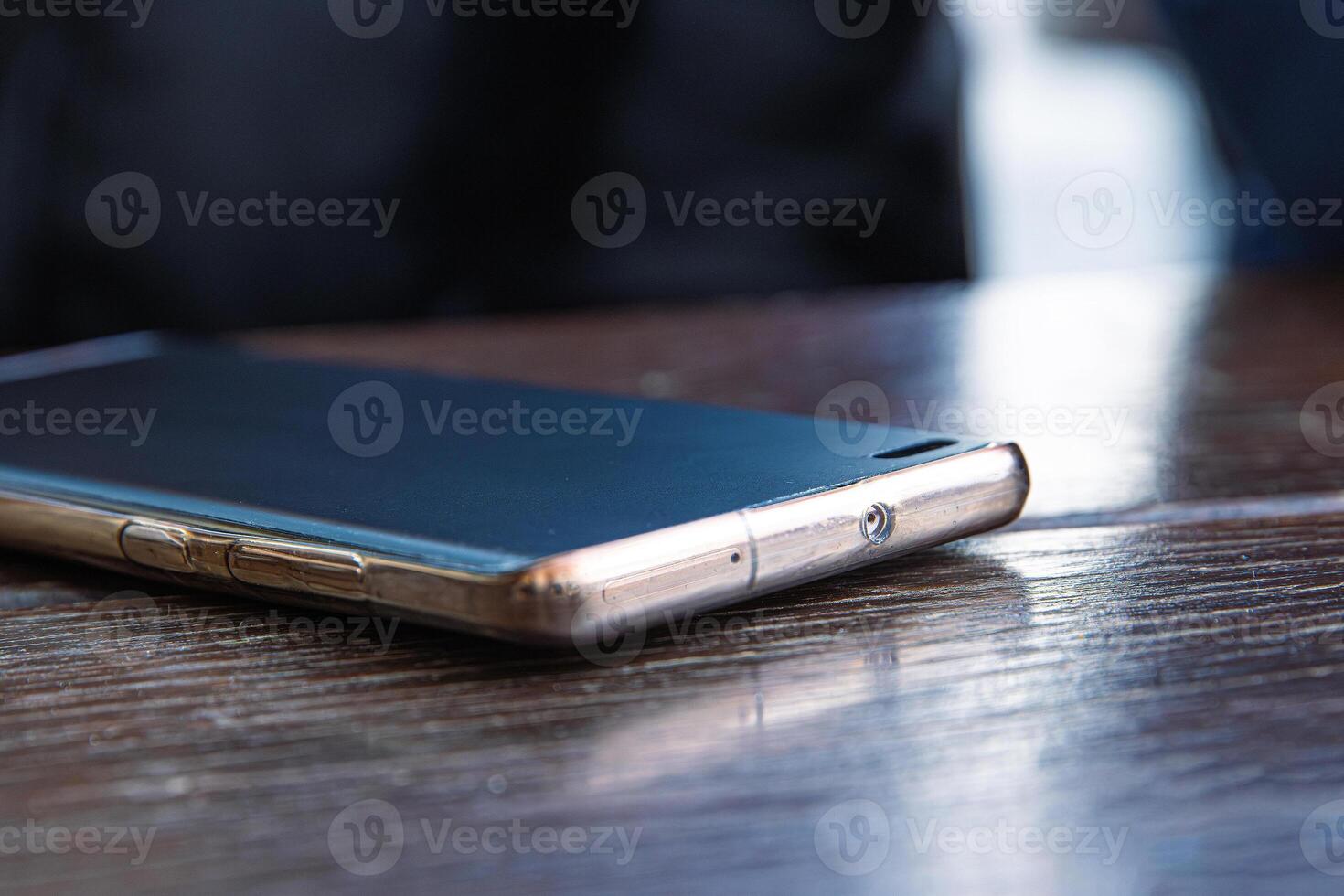 Closeup of the black screen smartphone on a dark brown wooden cafe table surface. Selective focus 03 photo
