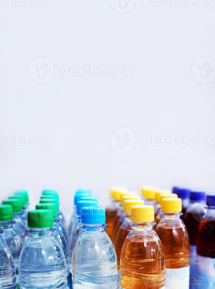 Plastic water and beverage bottles with multicolored caps arranged in rows for packaging and consumer product display. Selective focus 03 photo