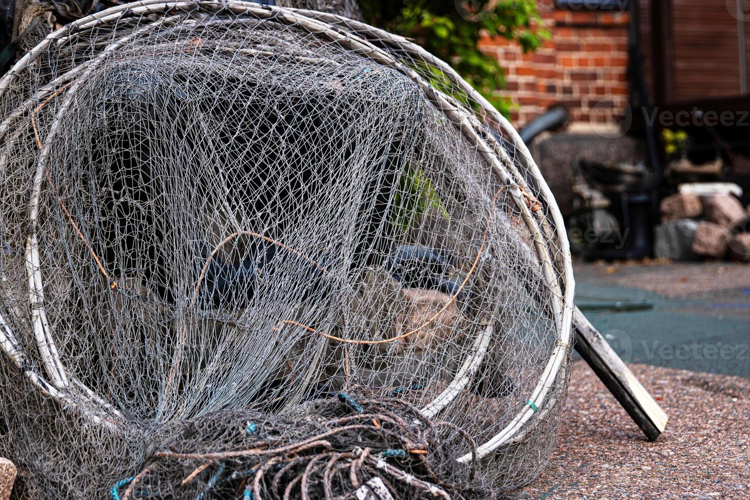 Fisher equipment. A weathered folded fishing hoop net and coiled wire and ropes on the ground, 22 photo