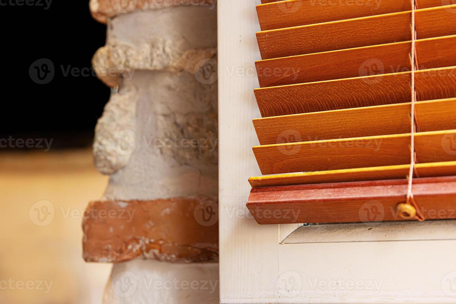 Closeup of a partially open wooden venetian blind next to a rustic textured wall made of brick and plaster. Selective focus 06 photo