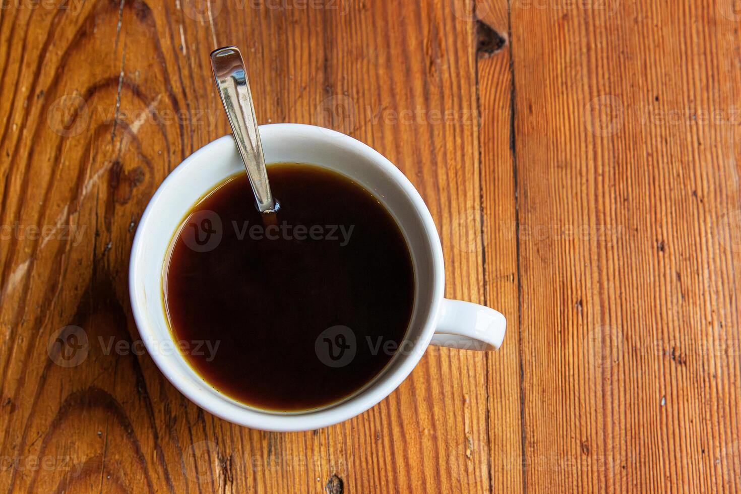 Minimalist top view of a white coffee cup with etal spoon placed on a textured wooden table or windowsill surface. 13 photo