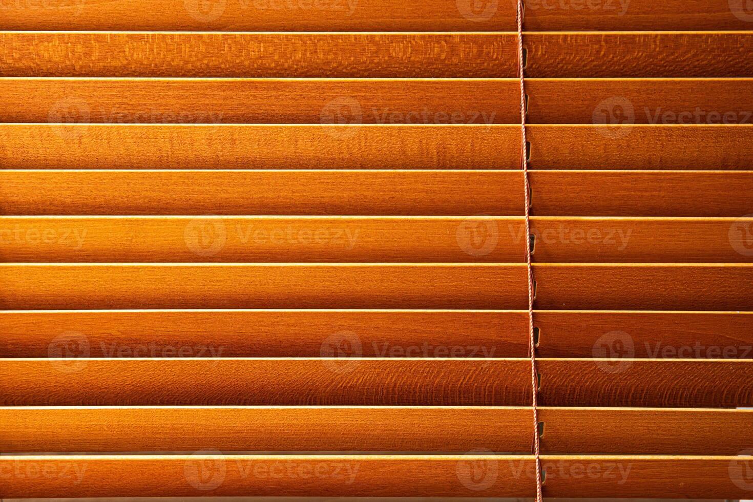 Minimalist closeup of wooden venetian blinds with warm tones and visible slats, capturing natural materials and a peaceful indoor atmosphere. photo
