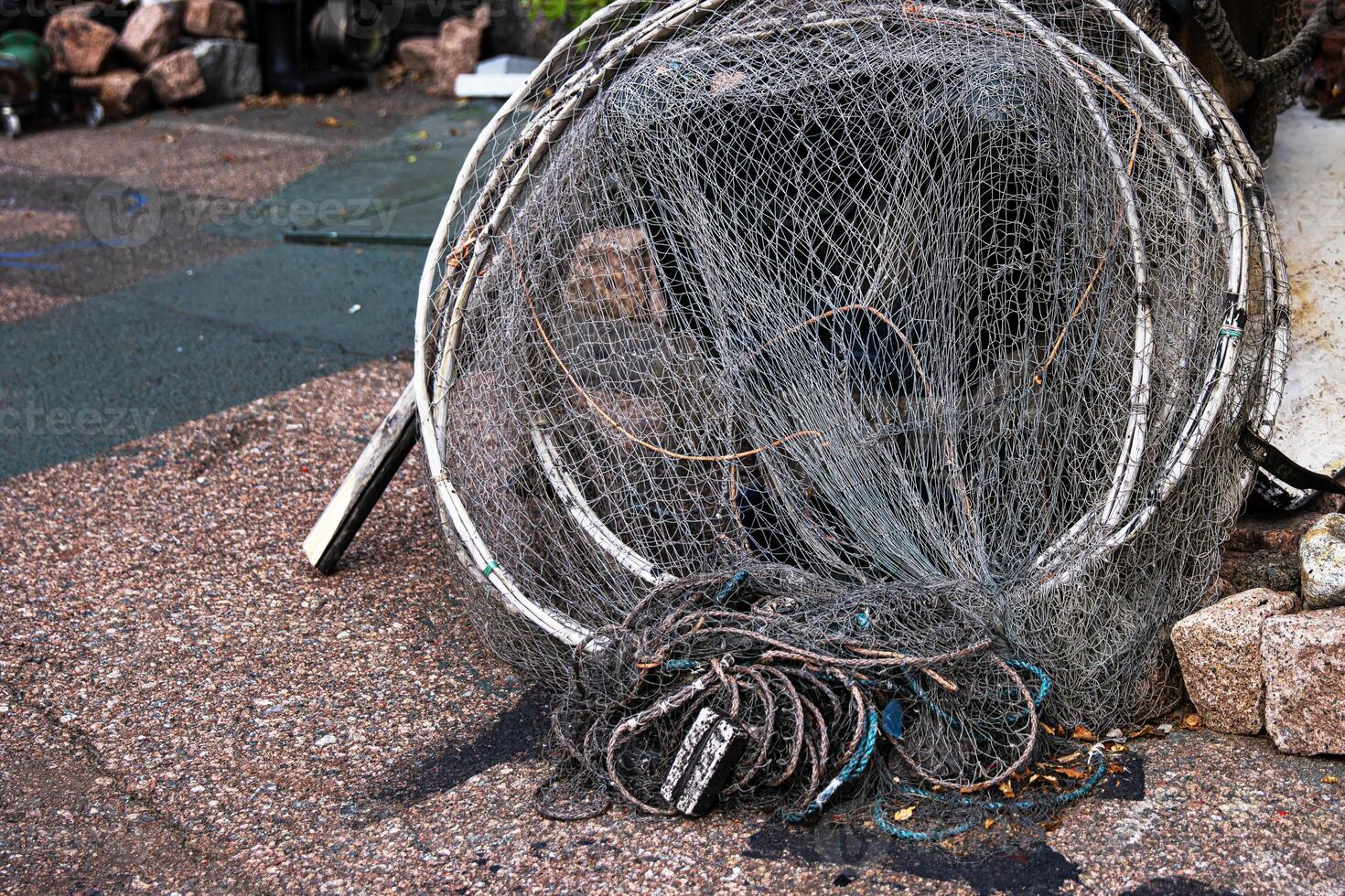 Fisher equipment. A weathered folded fishing hoop net and coiled wire and ropes on the ground, 04 photo