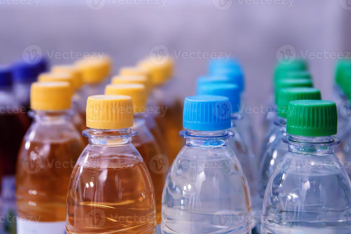Plastic water and beverage bottles with multicolored caps arranged in rows for packaging and consumer product display. Selective focus 01 photo