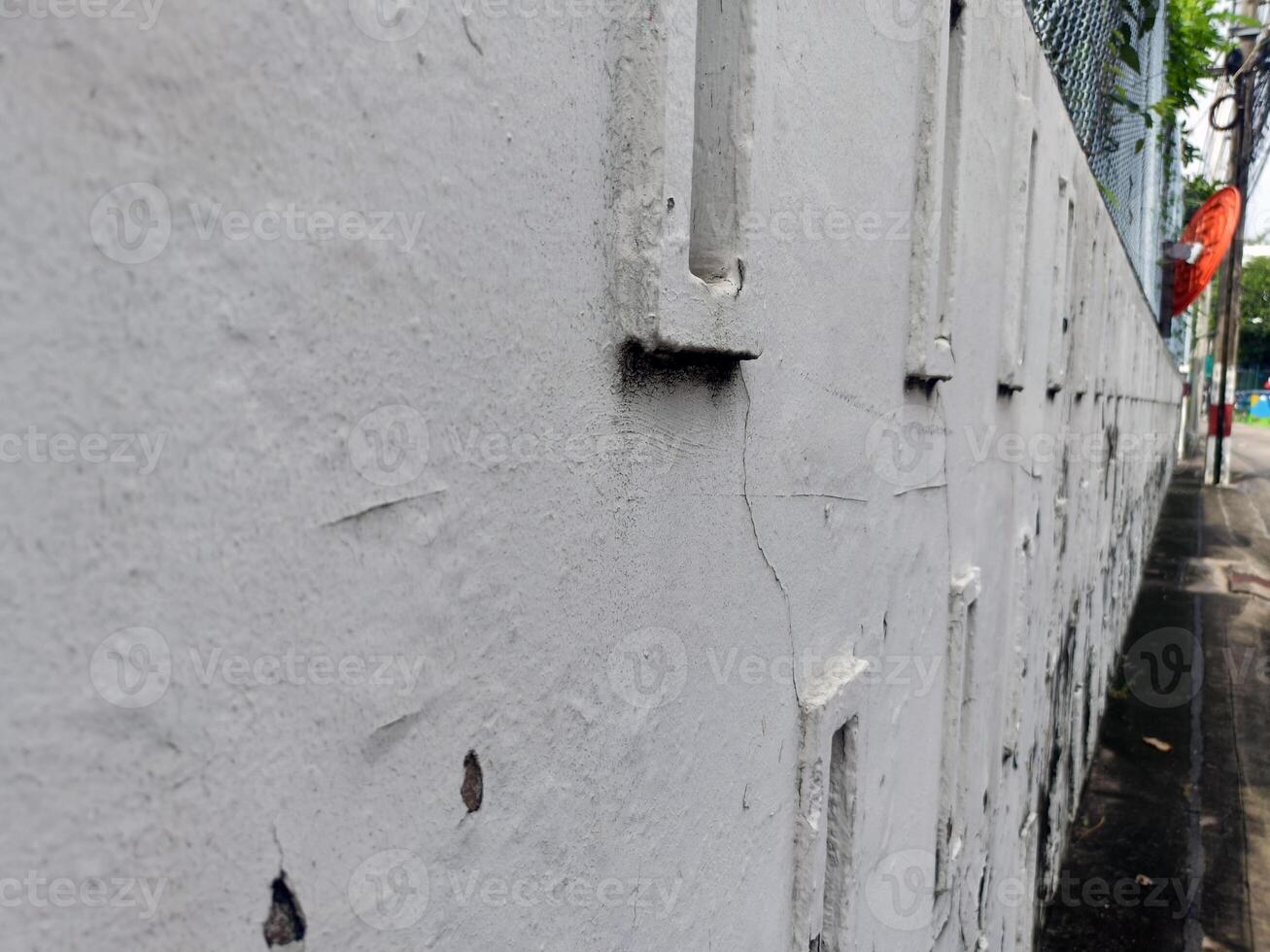 A textured gray wall appears aged and weathered with visible cracks, evoking sense of history and urban decay along street photo