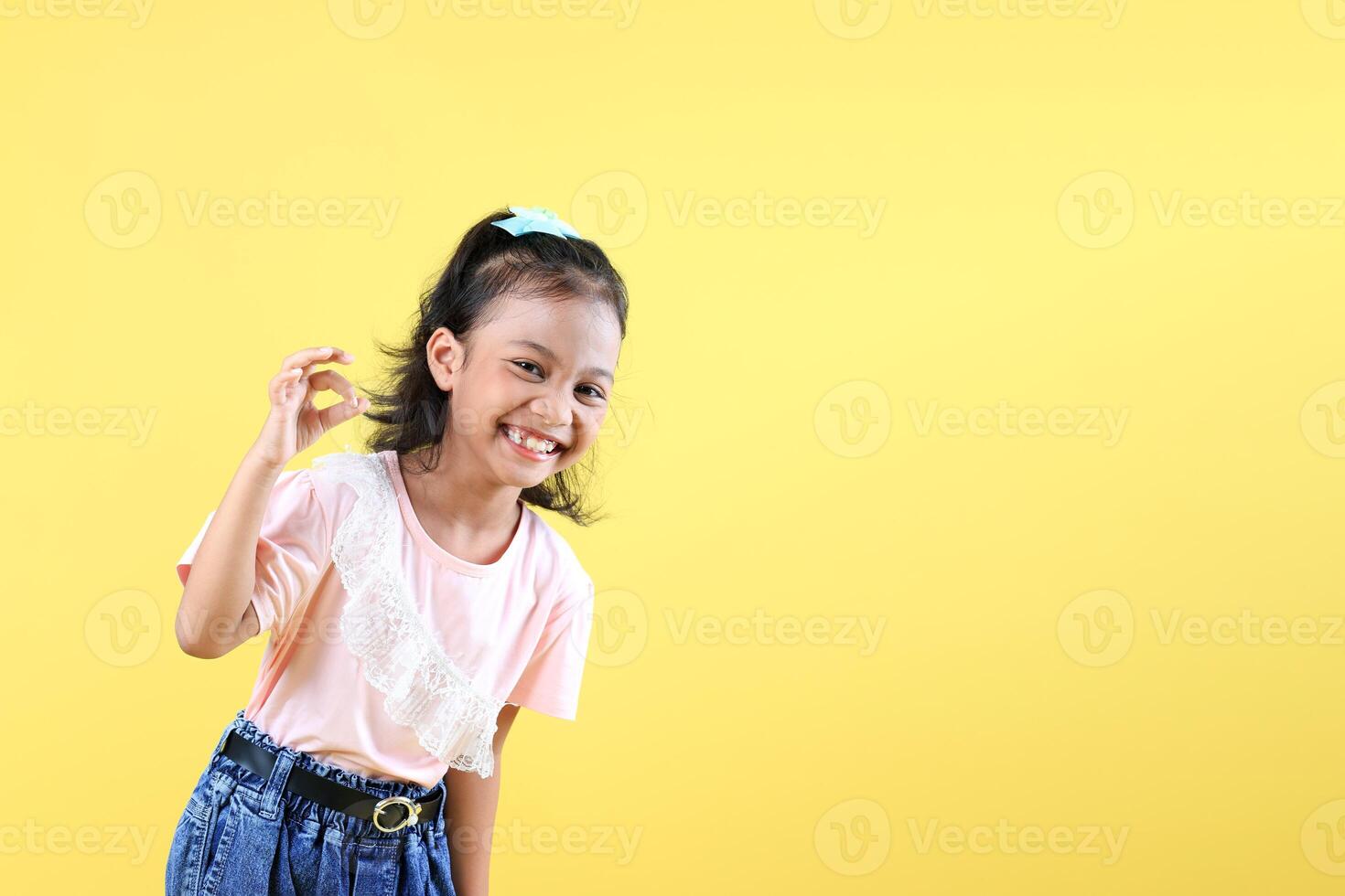 Happy Cheerful Girl Wearing Pink Shirt and Jeans, Laughing, and Make Okay Gesture. photo