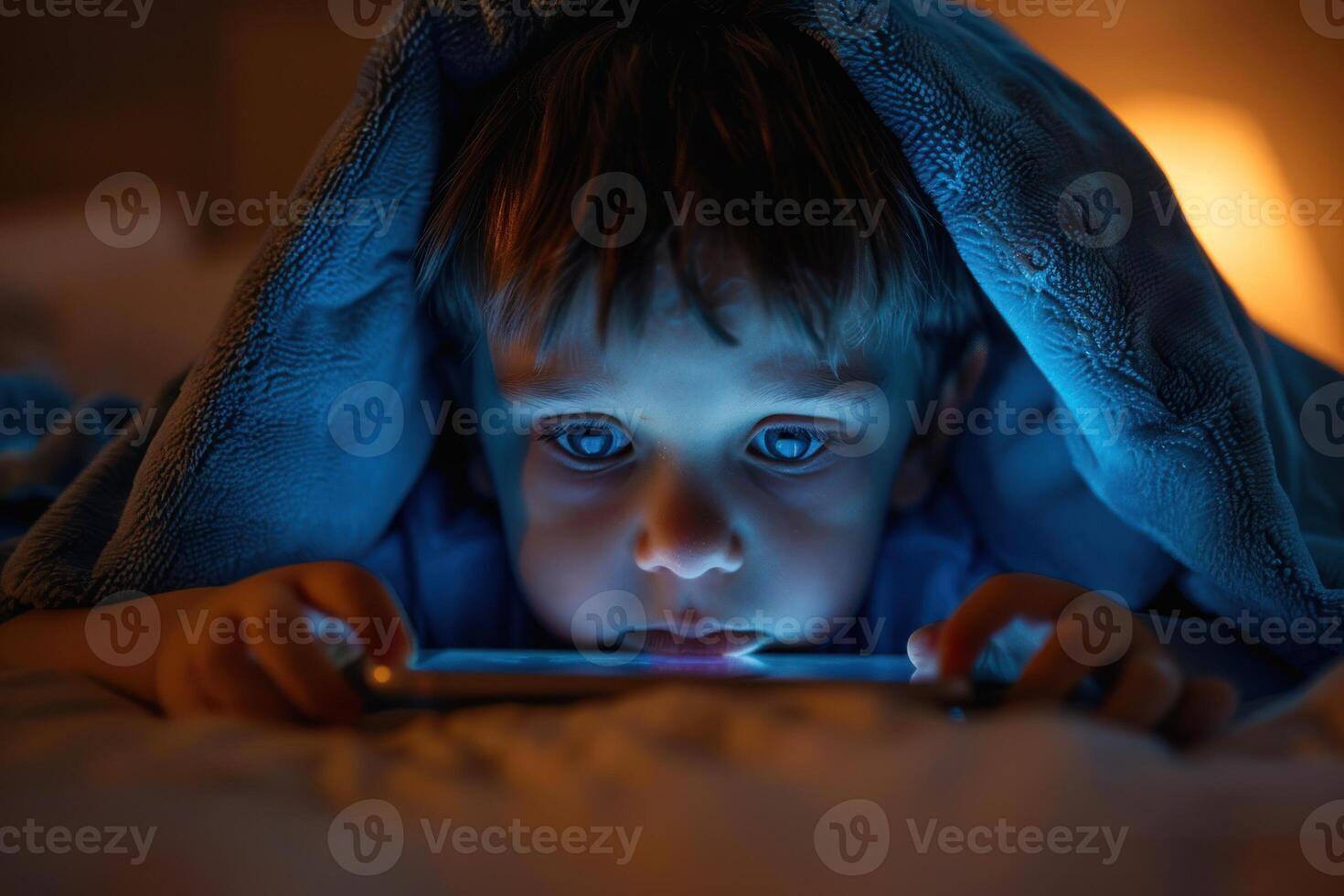 A young boy is playing with a tablet in bed photo