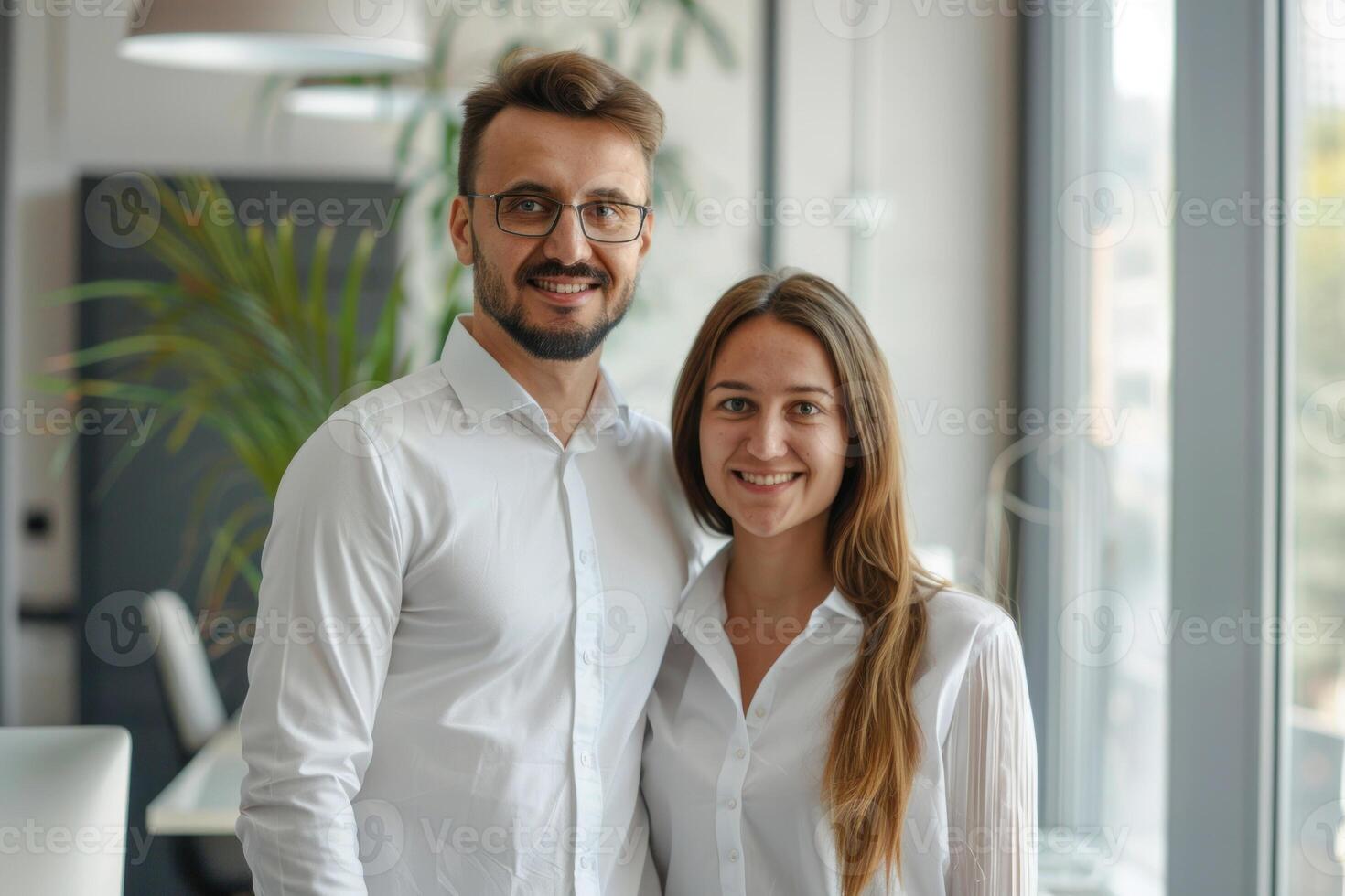 A man and woman in white shirts standing in front of a window photo