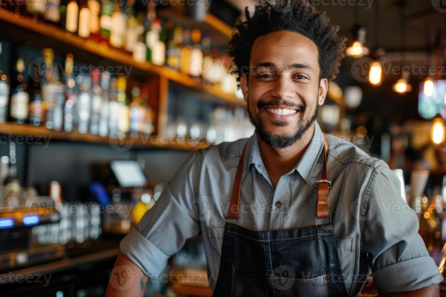 A smiling black man in an apron standing in front of a bar photo