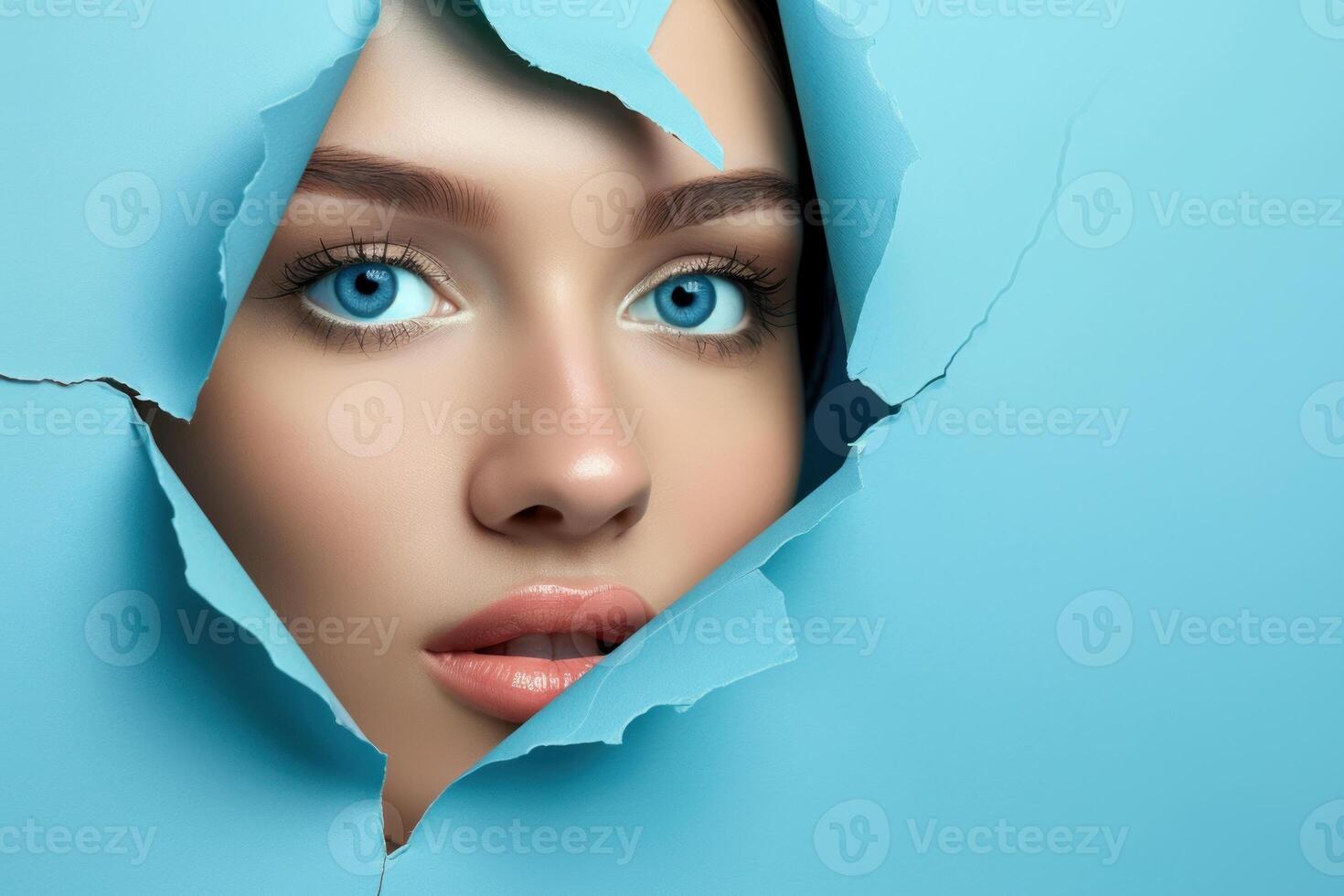 A woman's face peeking through a hole in a blue paper photo