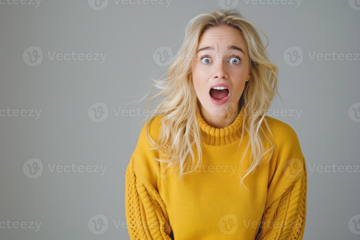 A woman in a yellow sweater is making a surprised face photo