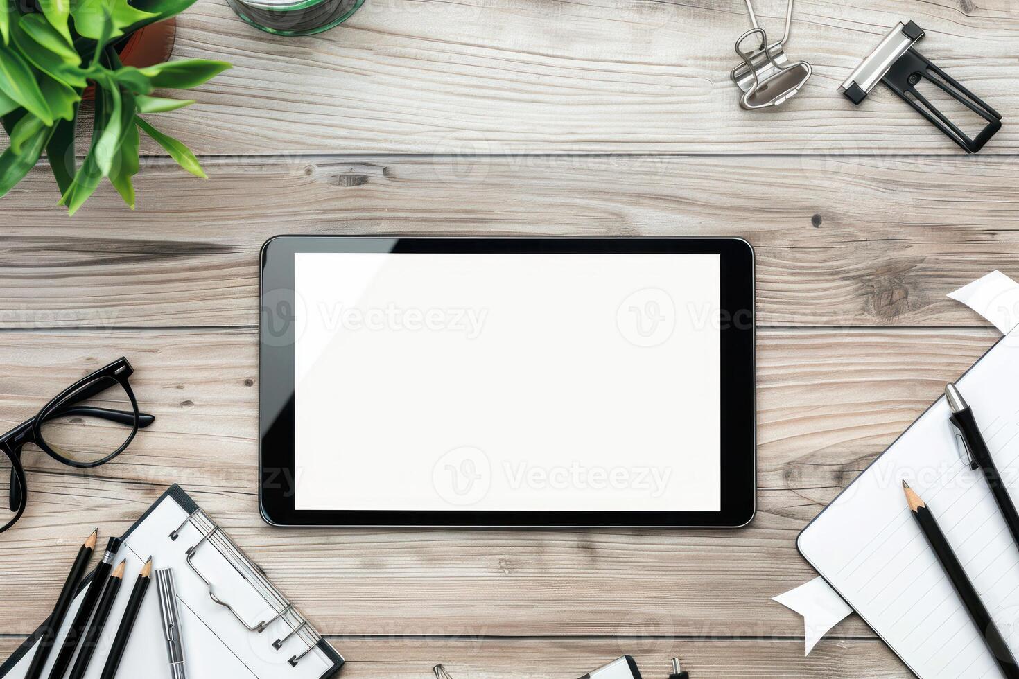Tablet with blank screen on wooden desk with office supplies photo