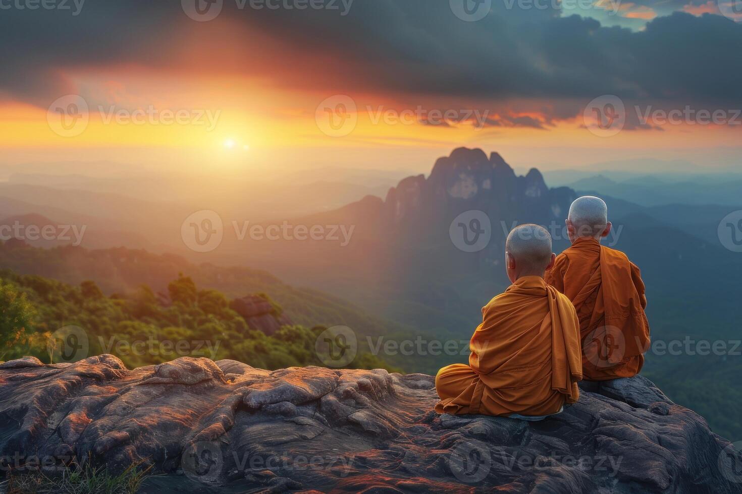 Two buddhist monks sitting on a rock at sunset photo