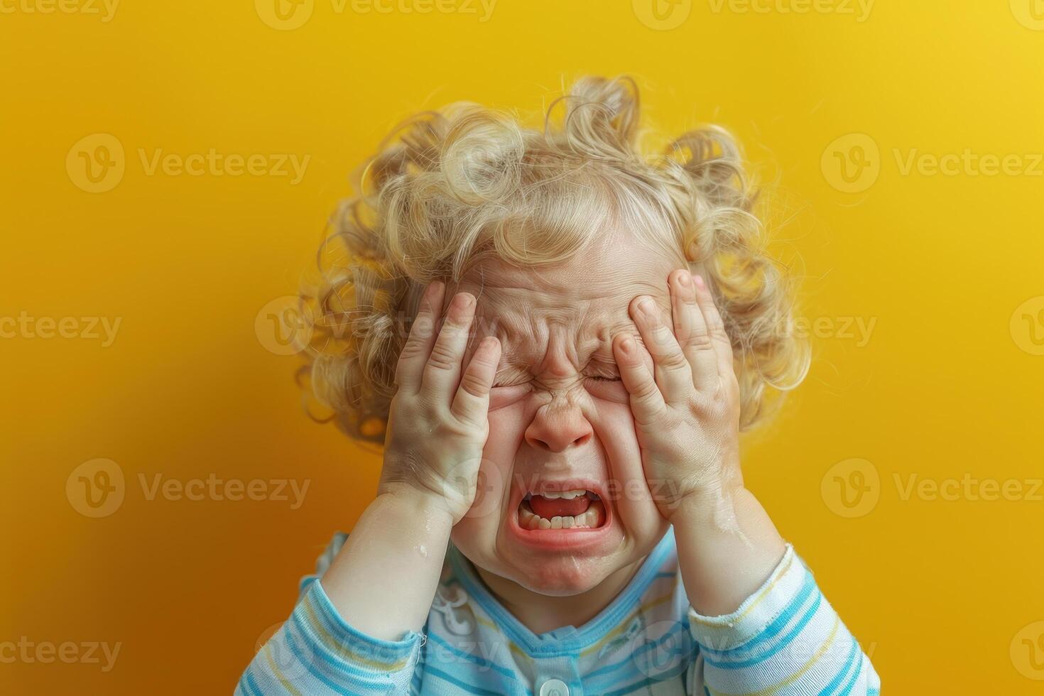 A child with his hands on his face and crying photo