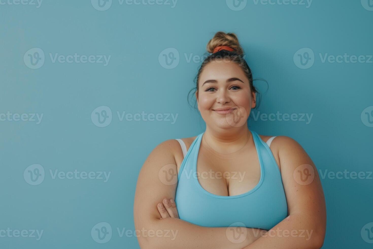 A woman in a blue sports bra top standing against a blue wall photo