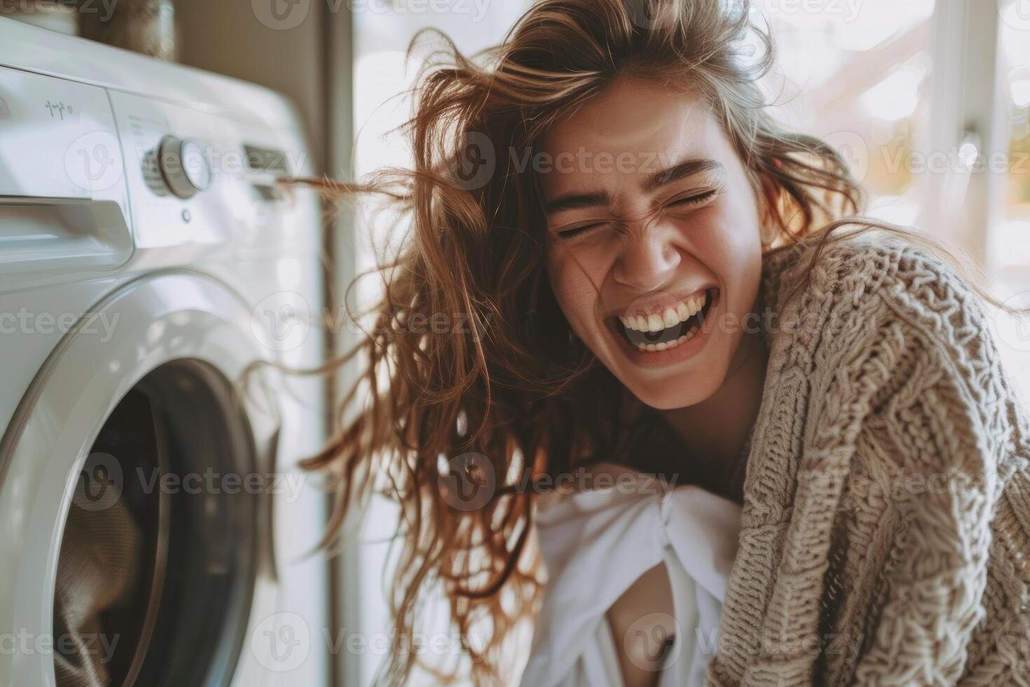 A woman laughing while she is in front of a washing machine photo