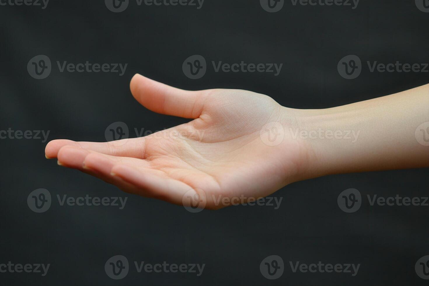 A person holding out their hand with a black background photo