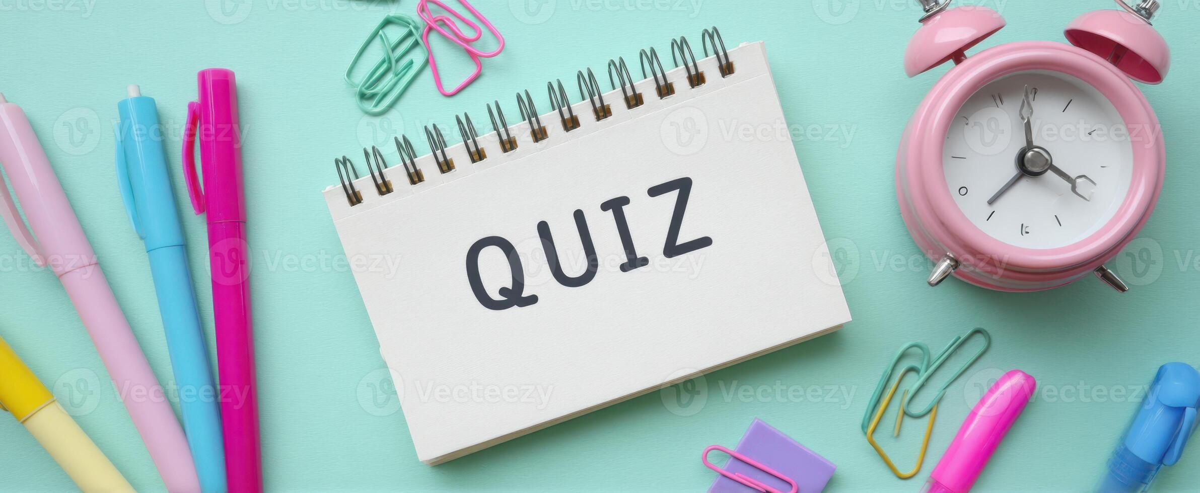 The Quiz Notebook Surrounded by Colorful Stationery and an Alarm Clock photo
