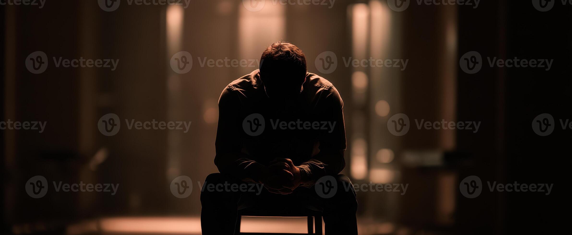 The man in silhouette contemplating his thoughts in a dimly lit space. photo