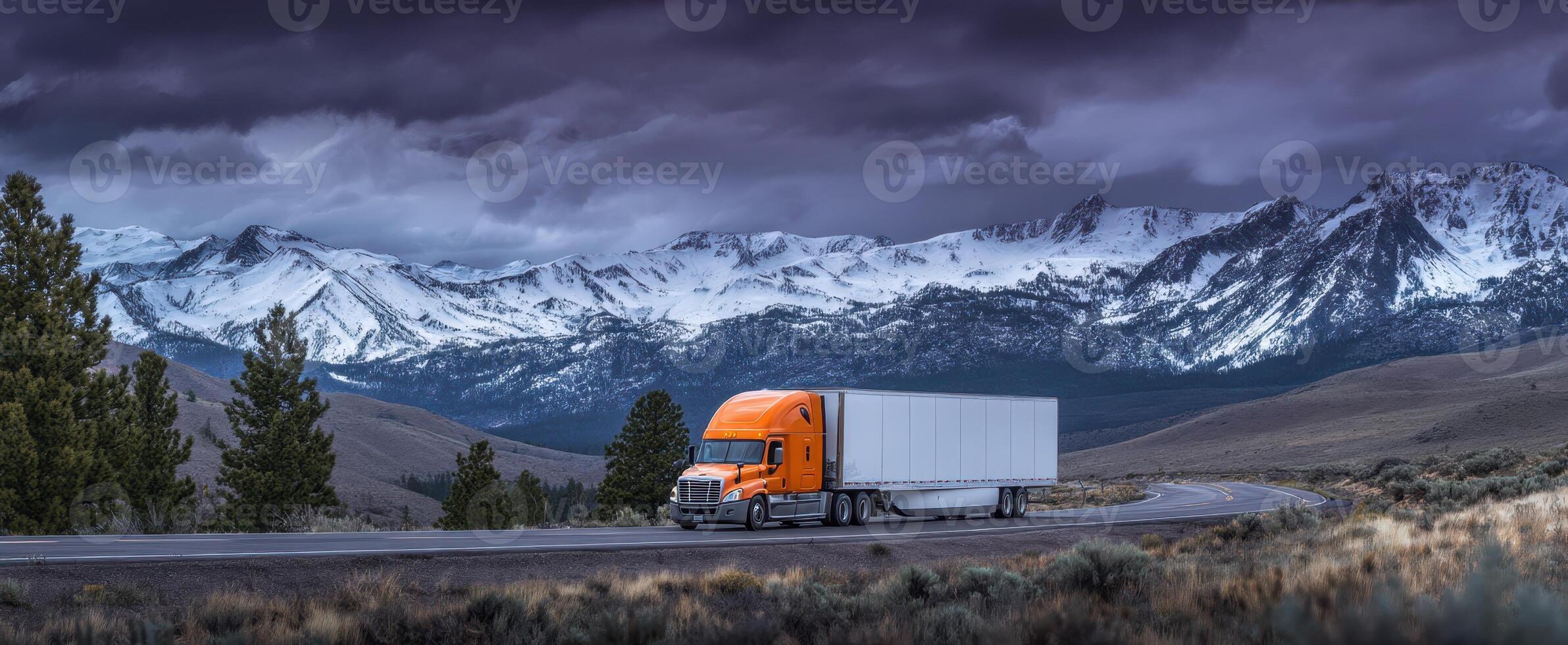 The striking orange truck against a backdrop of majestic snow-capped mountains. photo