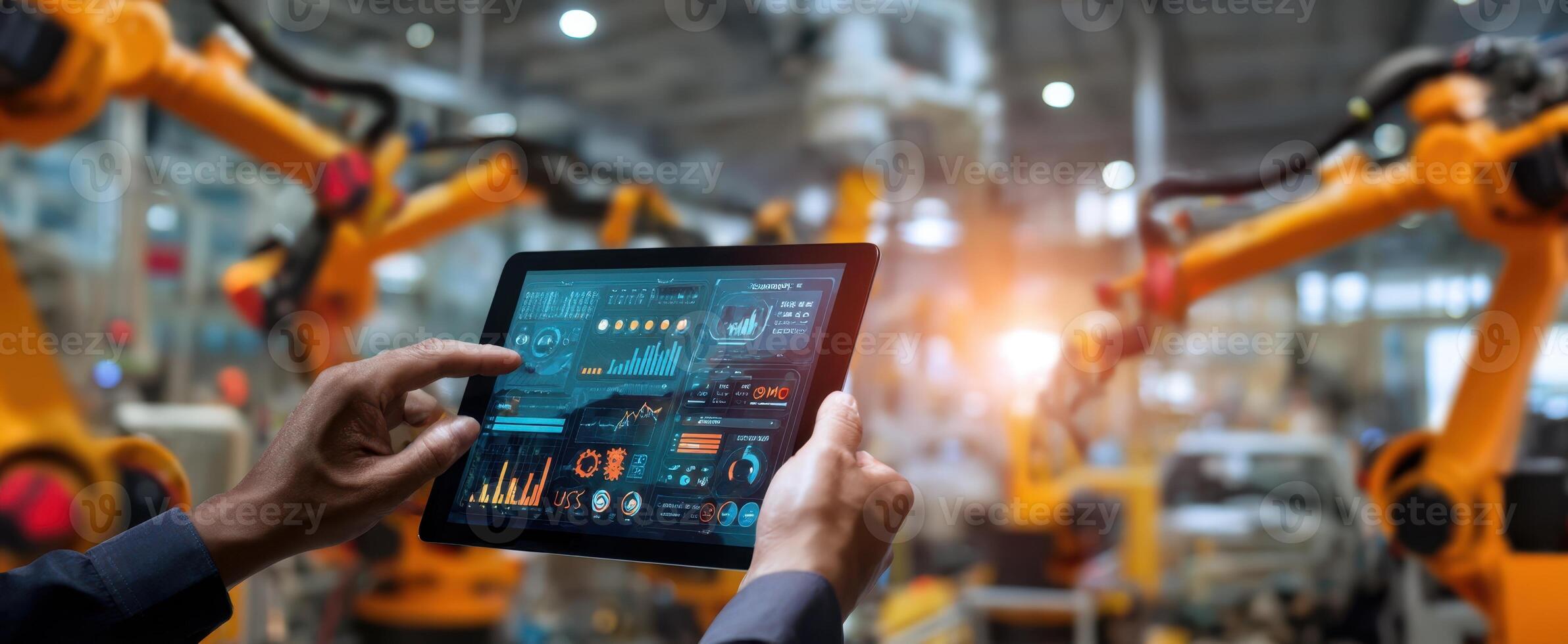 The tablet displaying analytics in an automated factory environment with robots. photo