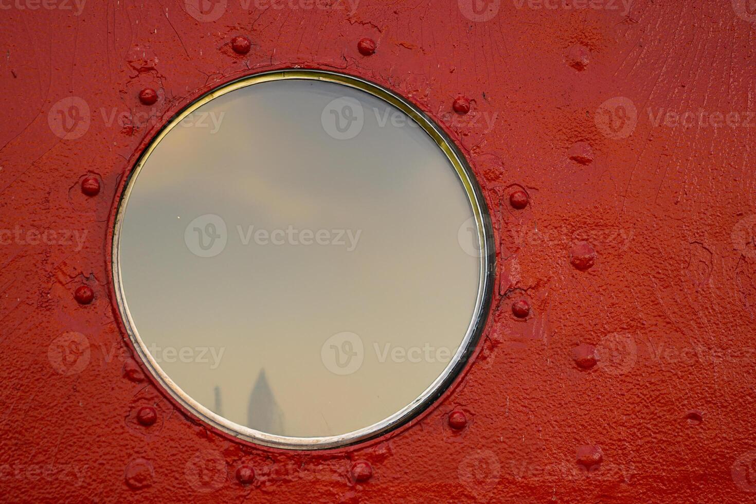 A detailed closeup of a round porthole with a protective glass with soft sky reflection. Brown painted old boat wall. 14 photo