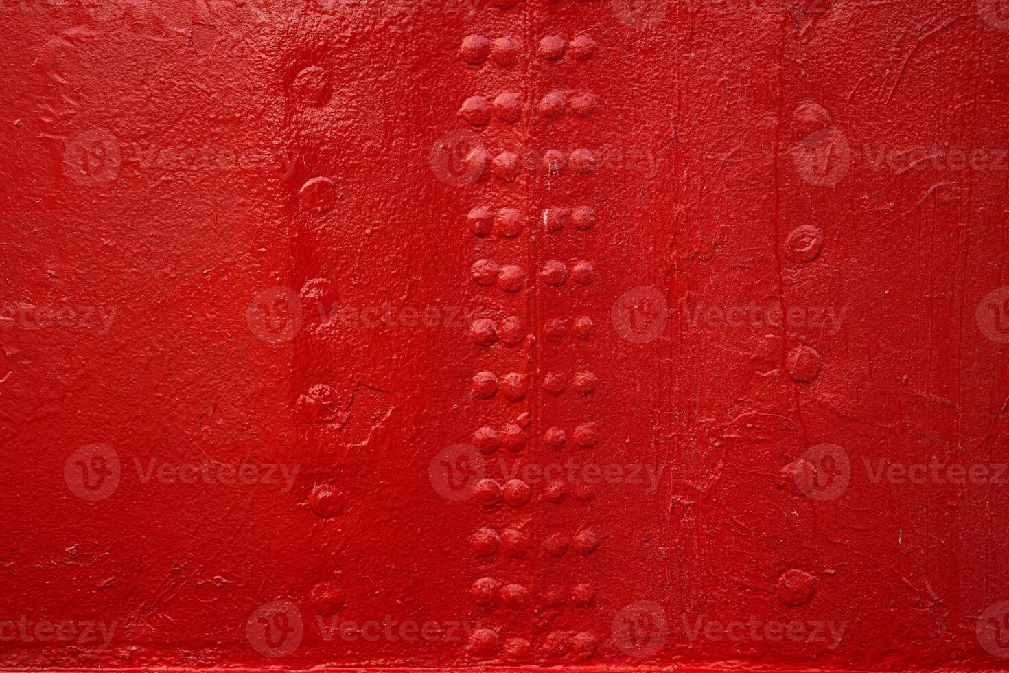 A closeup view of an industrial red painted metal surface with symmetrical rows of rivets, reflecting shipbuilding or machinery design textures 19 photo