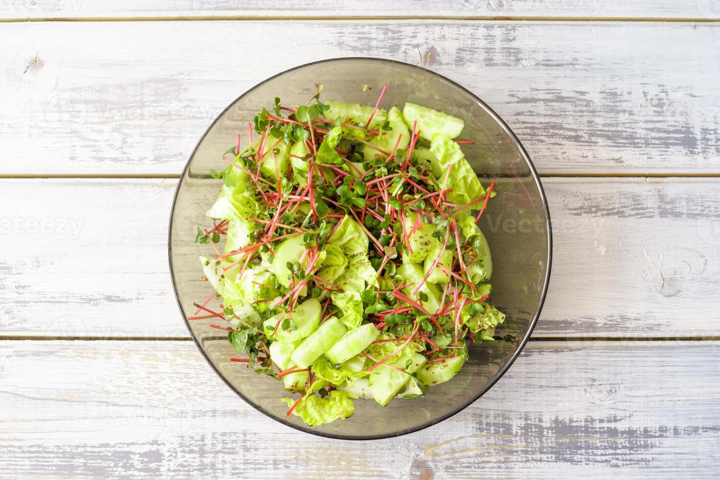 Top view to fresh green salad with red radish microgreens and vegetable mix. Healthy food and vegetarian lunch. Concept plant base diet for health lifestyle. photo
