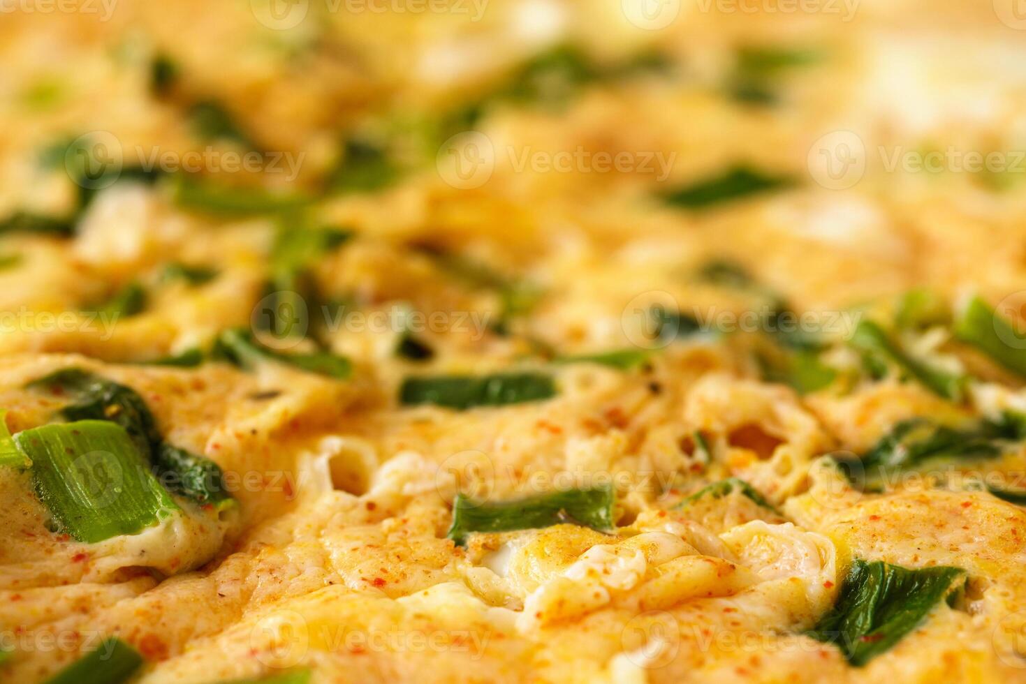 Macro shot of a homemade omelet cooked with fresh green onion slices. Delicious and healthy breakfast concept. Perfect for food blogs and recipe illustrations. photo