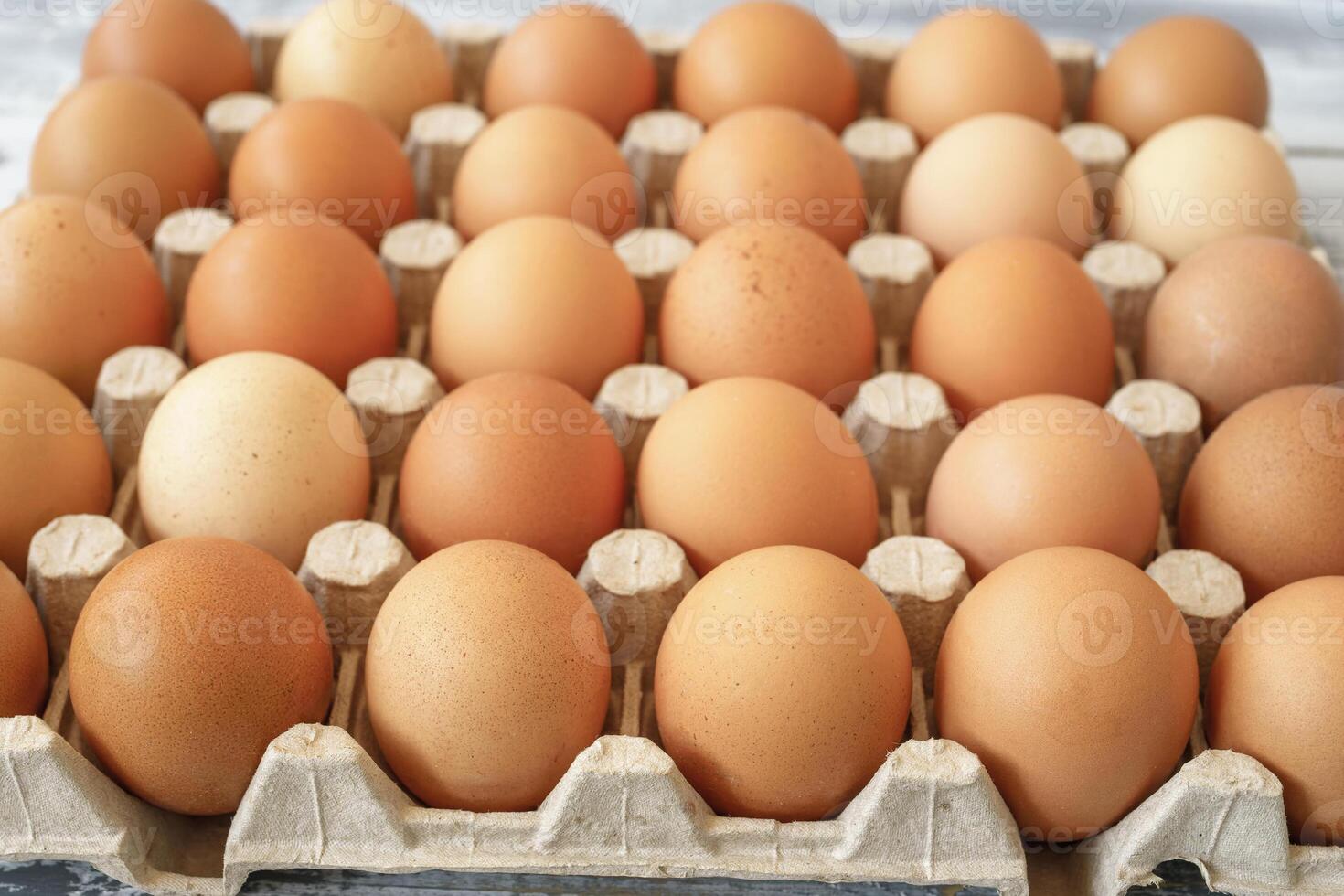 chicken eggs in a cardboard tray on a rustic wood background for farm and food concepts and healthy eating or cooking recipes and ingredients advertising. photo